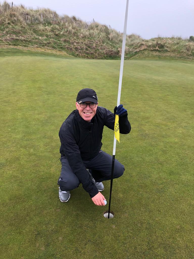 golfer in black kneeling on green